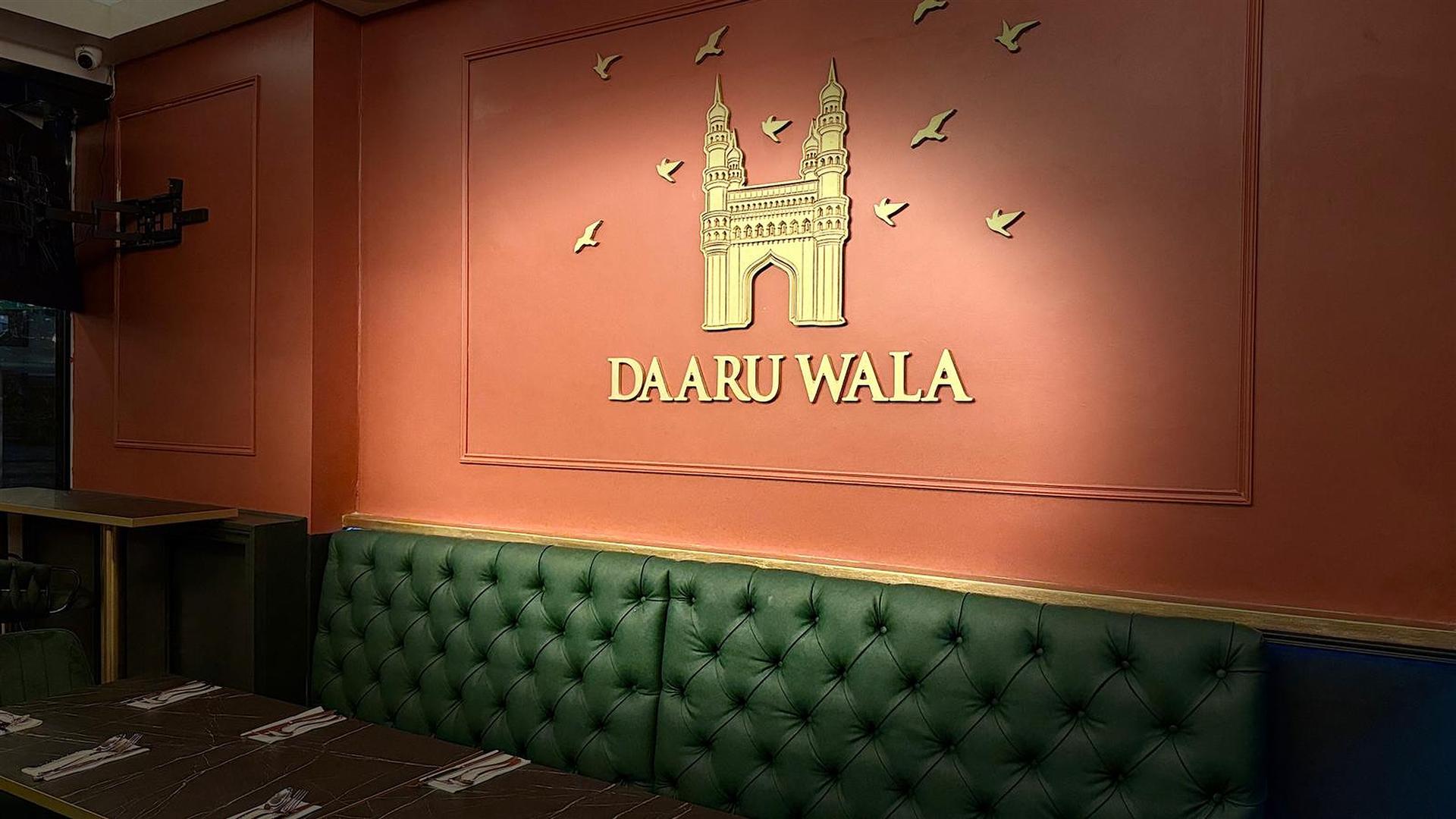 Elegant Charminar Daaru Wala wall logo in gold against our heritage red interior wall